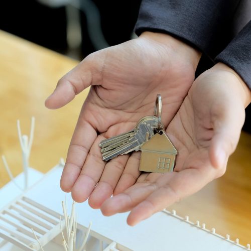 Real estate agent handing over house keys with approved mortgage application form and offer handshake.