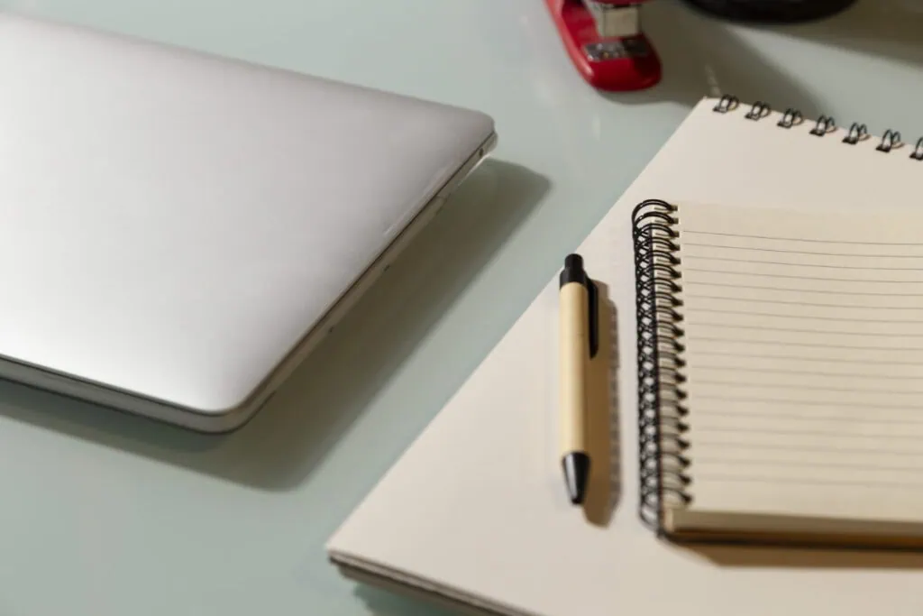 A notebook and pen near a laptop